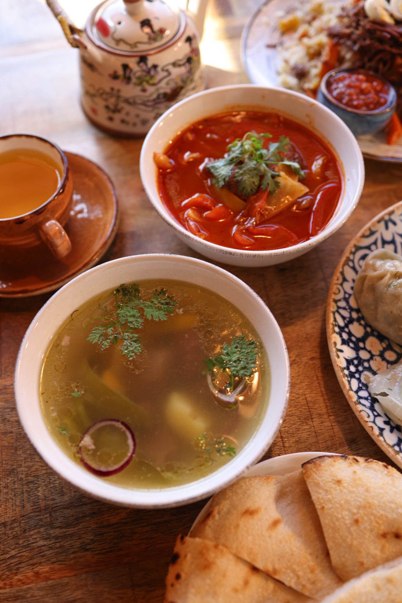 A vibrant mix of soups and side dishes showcasing international cuisine on a wooden table.