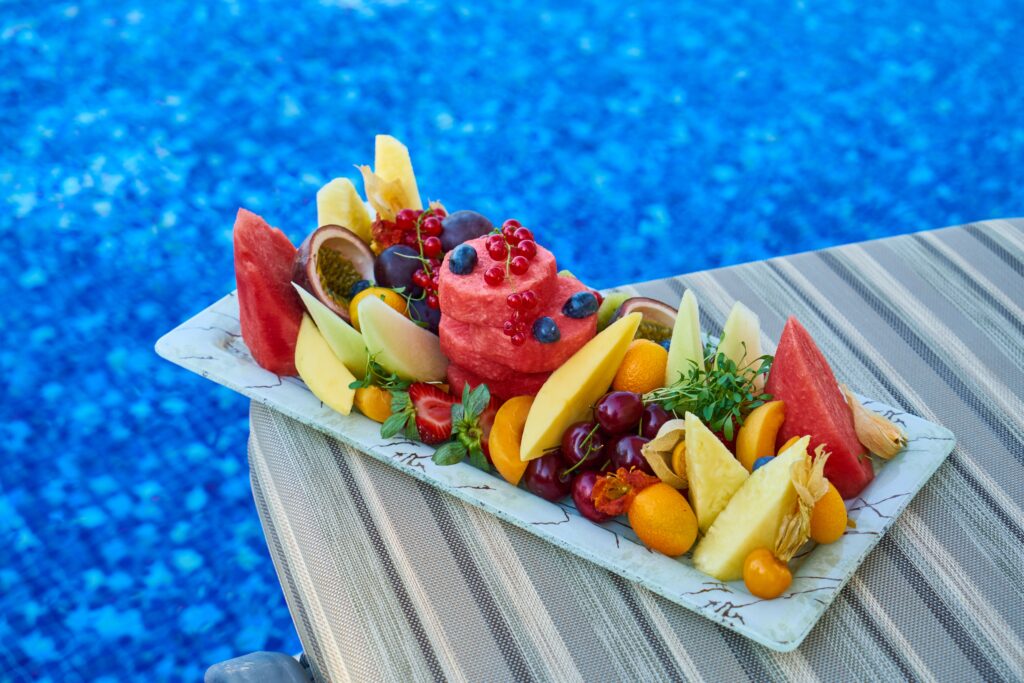Vibrant tropical fruit platter with delicious assortment by the blue pool.
